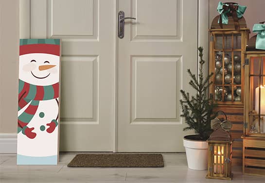 Vertical Christmas sign looking like a snowman placed near a door