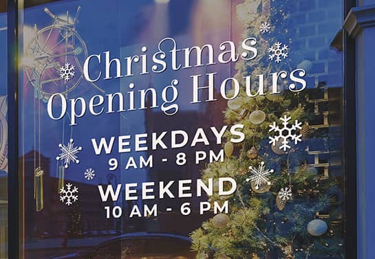 a simple Christmas store hours sign with white snowflakes