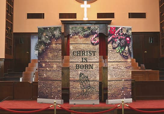 Three Church Christmas backdrops with the words Christ is born on a church stage