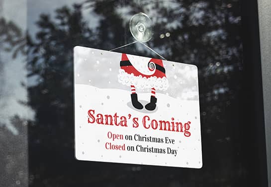 a white printable closed sign for Christmas with red lettering and Santa’s tiny legs