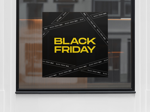Black Friday window sign with yellow text on black background and diagonal sale ribbons