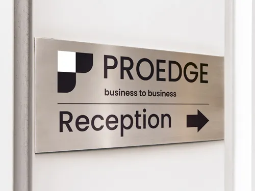 Aluminum sign for business reception area with company logo and directional arrow for wayfinding.