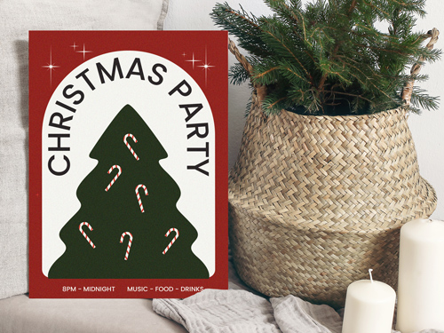Christmas party foam board sign with a stylized Christmas tree and candy canes, placed beside holiday décor and candles.