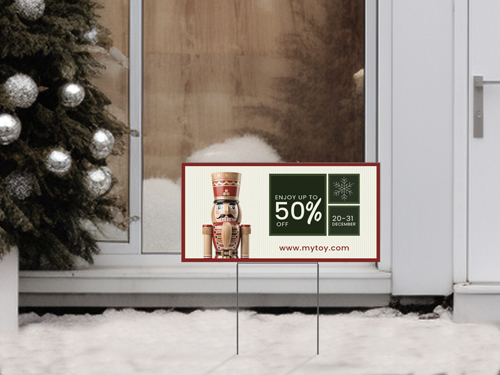 Christmas yard sign featuring a nutcracker illustration and up to 50% off sale offer set in a snowy outdoor scene.