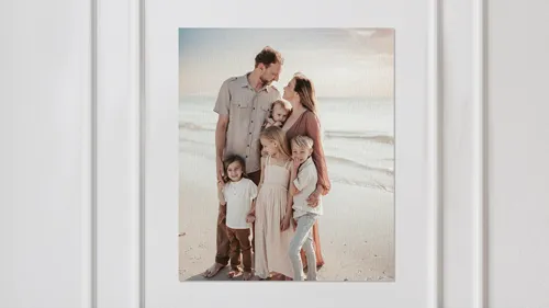 A canvas print of family portrait showing parents with two children on beach.