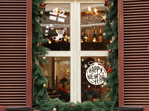 Christmas window decorated with white holiday decals, gift box, candy cane, stocking, and “Happy New Year” ornament, surrounded by festive garland.