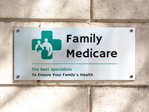 Family Medicare aluminum sign mounted on an exterior wall, featuring medical logo and text for clinic identification and branding.