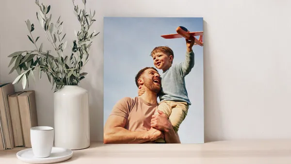 A foam board print of a father-son duo having fun outside with an RC plane.