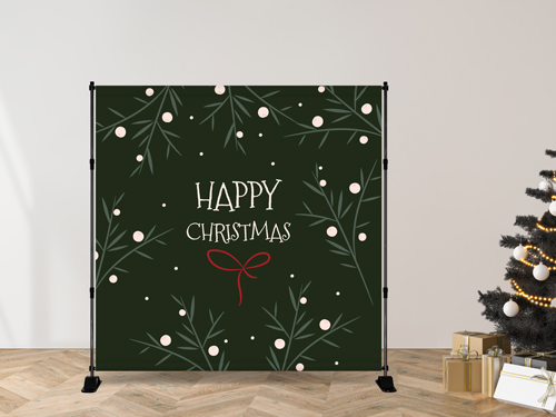 Green Christmas party backdrop with festive branches and “Happy Christmas” text set up beside a decorated tree.