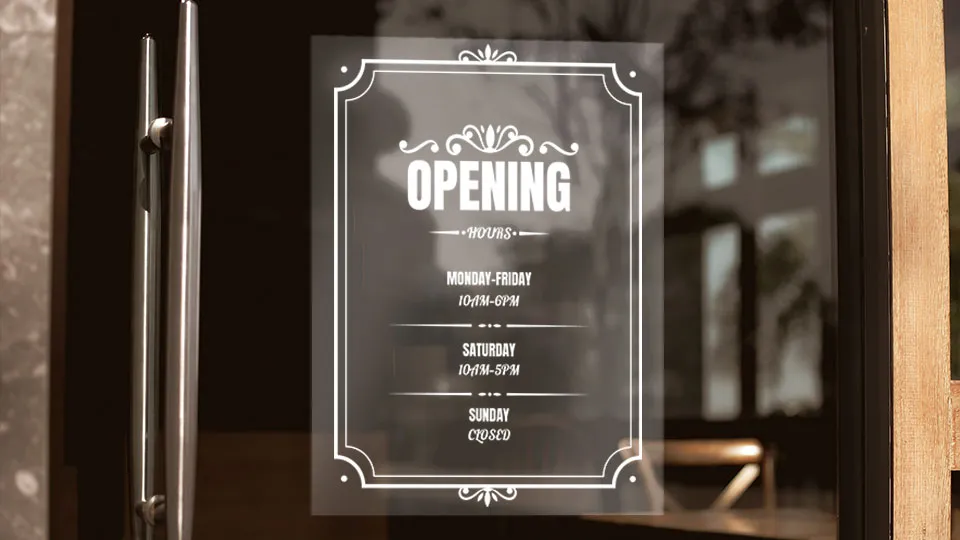 A clear static cling showcasing restaurant business hours adhered to the glass surface