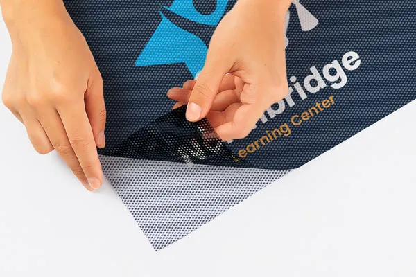 A dark blue perforated window decal for a learning center being peeled off its backing