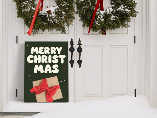 Merry Christmas PVC sign with a gift box illustration leaning against a snowy front door decorated with holiday wreaths.