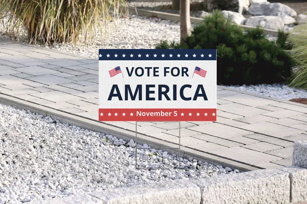 Corrugated plastic sign reading Vote For America with flags on both sides.