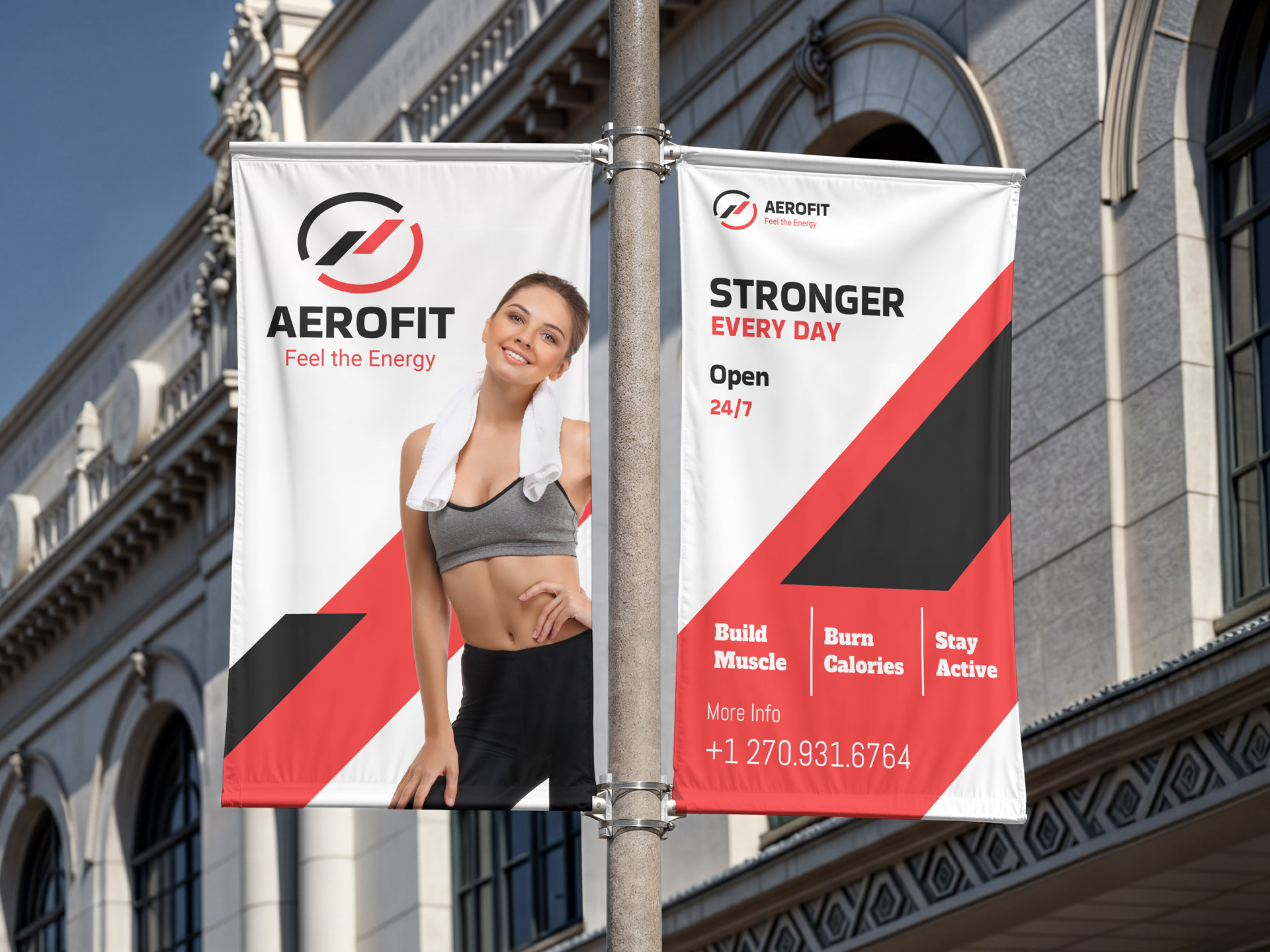 Two vertical fitness banners mounted on a street pole outside a building.