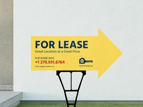 A yellow For Lease yard sign set up in front of a property directing people towards the entrance.