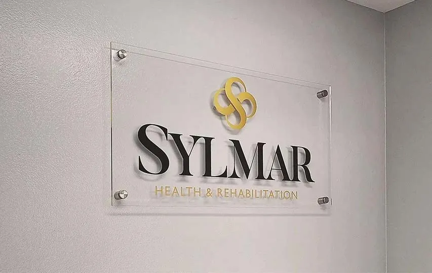 A clear acrylic plaque with a golden logo and the brand name printed underneath it.