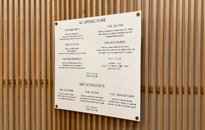 A white acrylic plaque mounted on a wooden wall showcasing physiotherapy services.