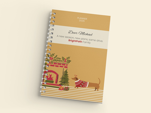 Holiday-themed 2026 planner with dog, fireplace, and Christmas tree illustration on a spiral-bound cover.