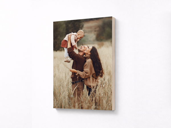 A family portrait of parents carrying their child in an open field printed on a wooden sign.