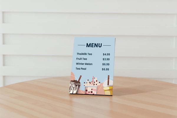 A café menu printed on a PVC board placed in a leaning position on a table.