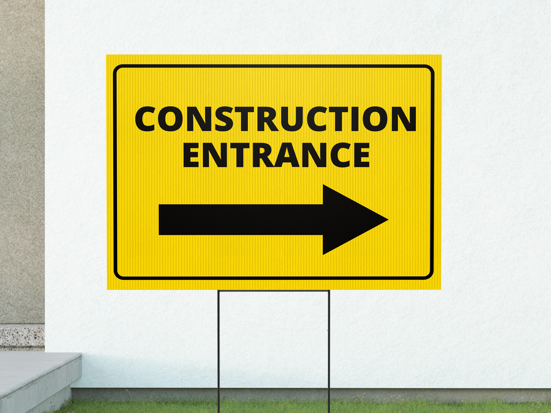 A black and yellow yard sign with the words construction entrance and a black yellow pointing towards the right.