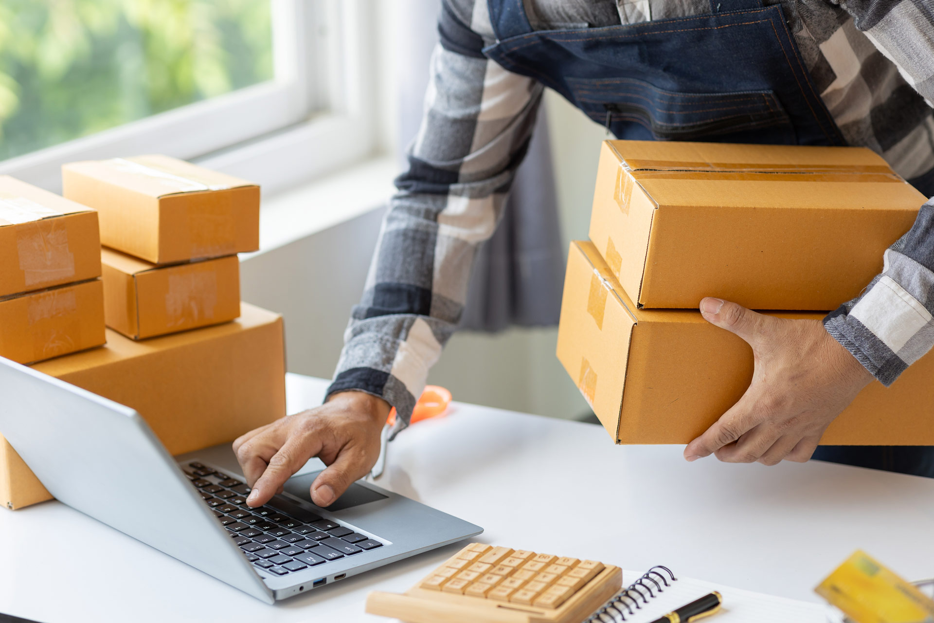 An image of a person processing packages using a computer.